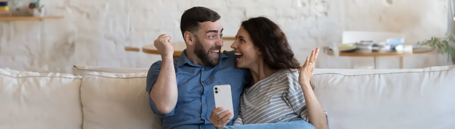 Lachendes Pärchen auf der Couch mit Handy