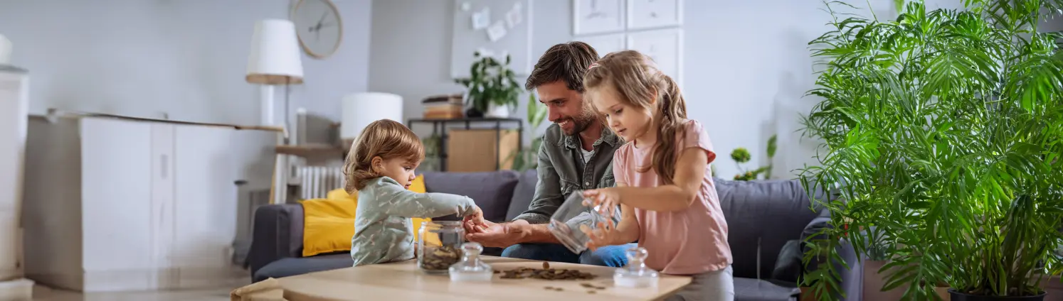 Ein Vater mit zwei kleinen Kindern zählt am Küchentisch Münzen