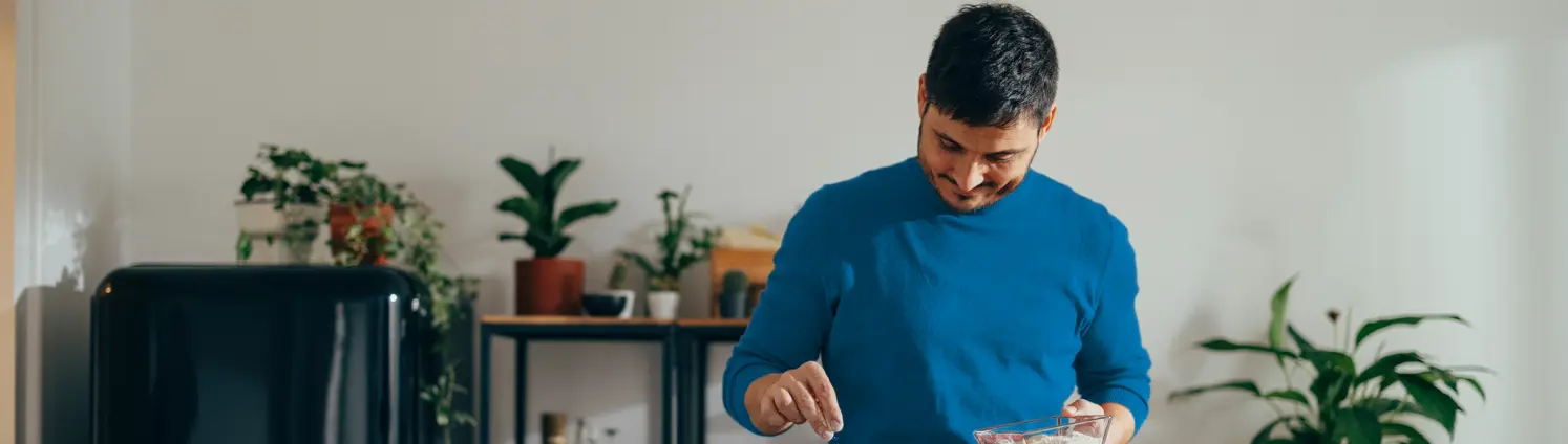 Mann mit blauem Pullover kocht in der Küche