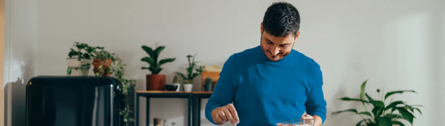 Ein Mann in blauem Pullover kocht an einem Gasherd in seiner Küche