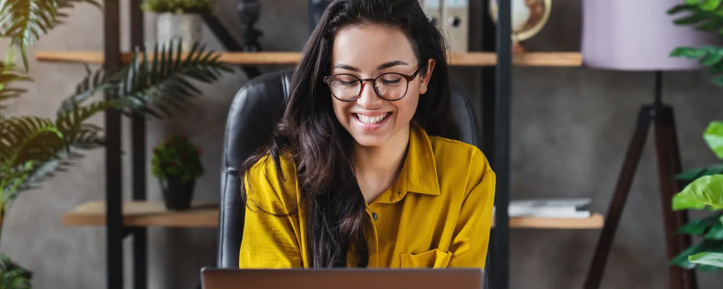 Eine Geschäftsfrau sitz am Arbeitsplatz und ließt was auf ihrem Laptop