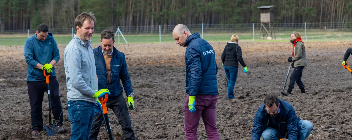 Mehrere Menschen stehen auf einem Acker und haben Schippen in der Hand