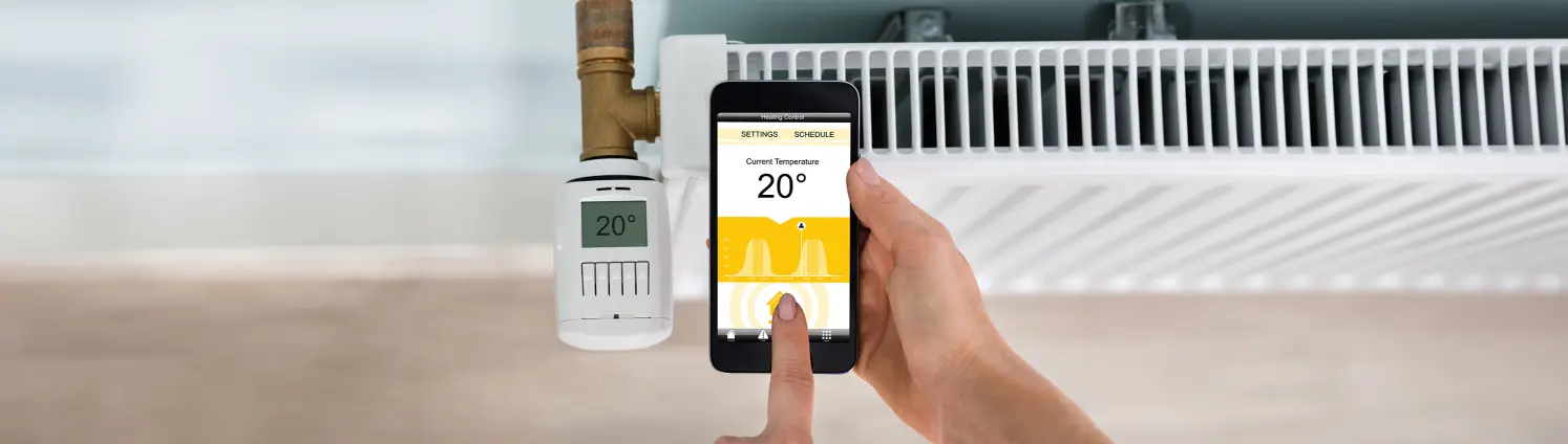 Heizkörper mit digitalem Thermostat, der über eine mobile App gesteuert wird.