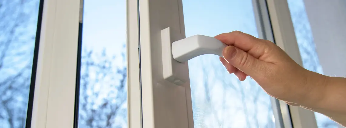 Eine Hand öffnet ein Fenster im Winter