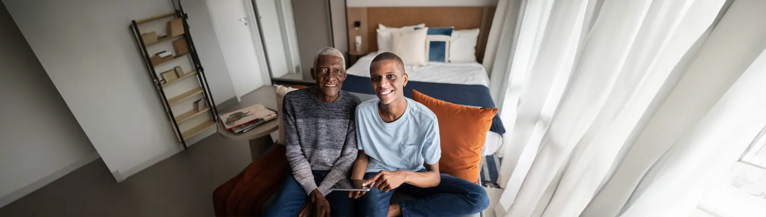 Vater und Sohn sitzen auf einem Bett und lächeln