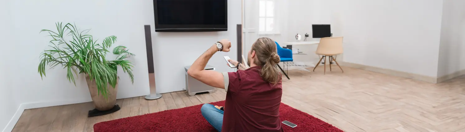 Ein Mann versucht in einem Wohnzimmer den Fernseher einzuschalten