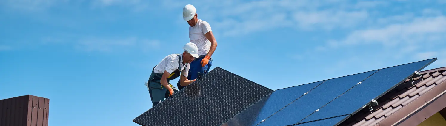 Zwei Männer installieren eine Solaranlage auf dem Dach