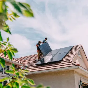 Junge Hausbesitzer installieren Solarmodule auf einem Haus