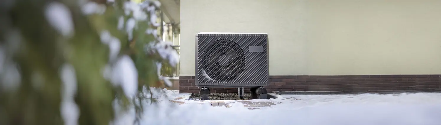 Wärmepumpe an einer Hauswand im Schnee