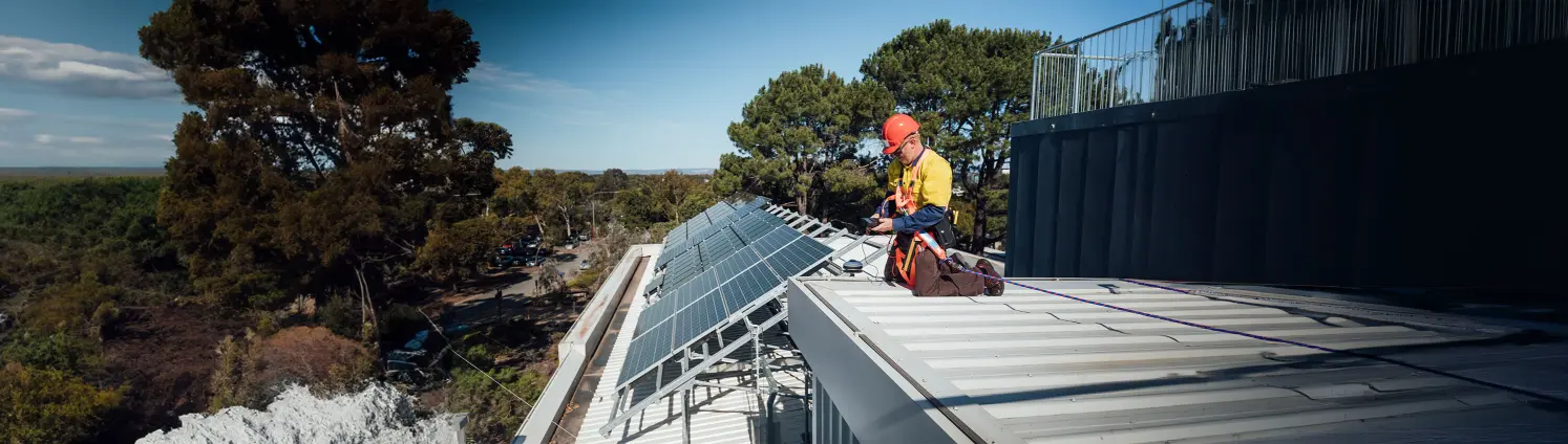 Ein Techniker prüft eine Photovoltaikanlage auf einem Dach