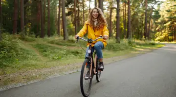 Eine Frau fährt mit dem Fahrrad durch einen Wald