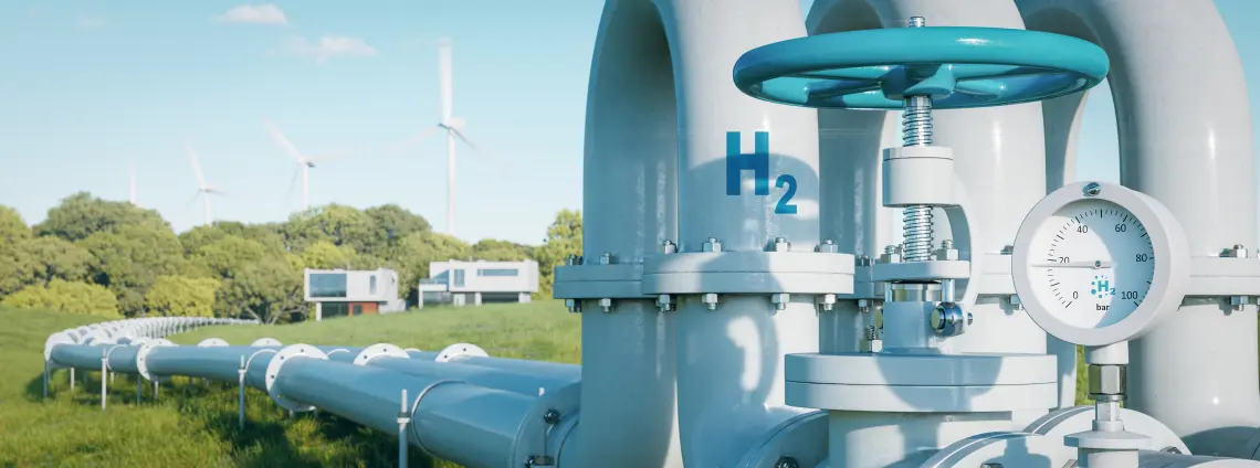 Wasserstoff-Rohre auf einer Wiese als Teil der Wasserstoff-Infrastruktur mit Windrädern im Hintergrund