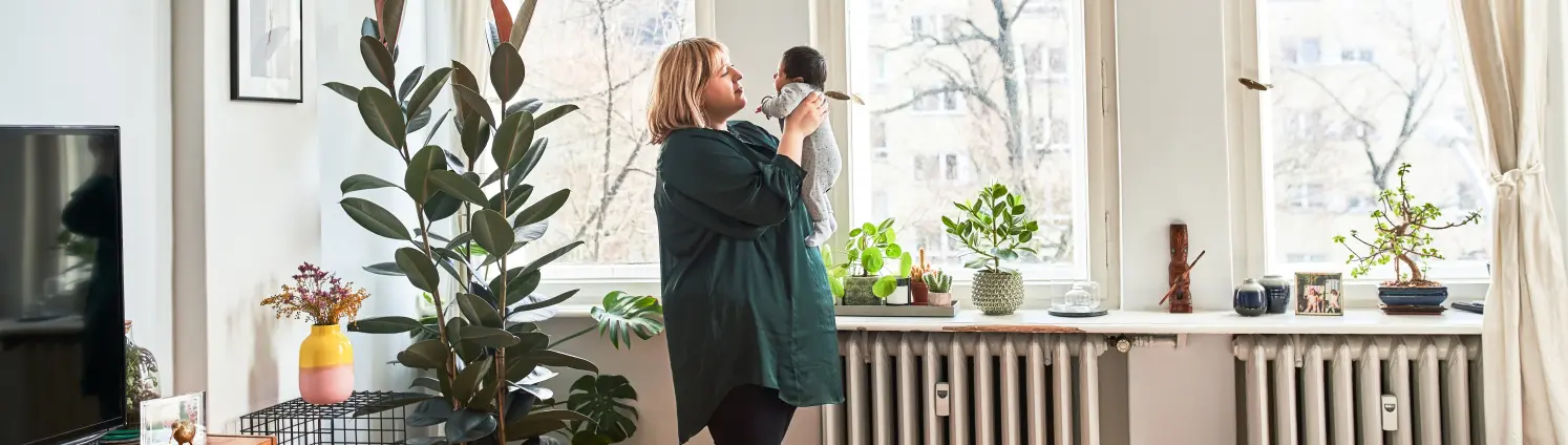 Eine Frau steht mit ihrem Baby in einem Wohnzimmer