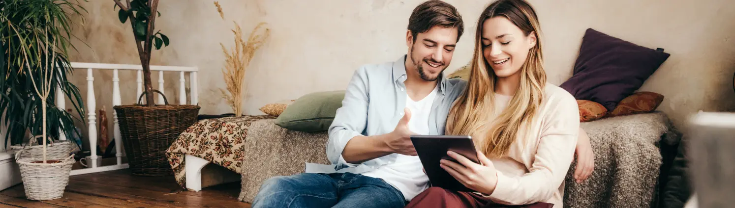 Mann und Frau sitzen an einem Tablet zusammen