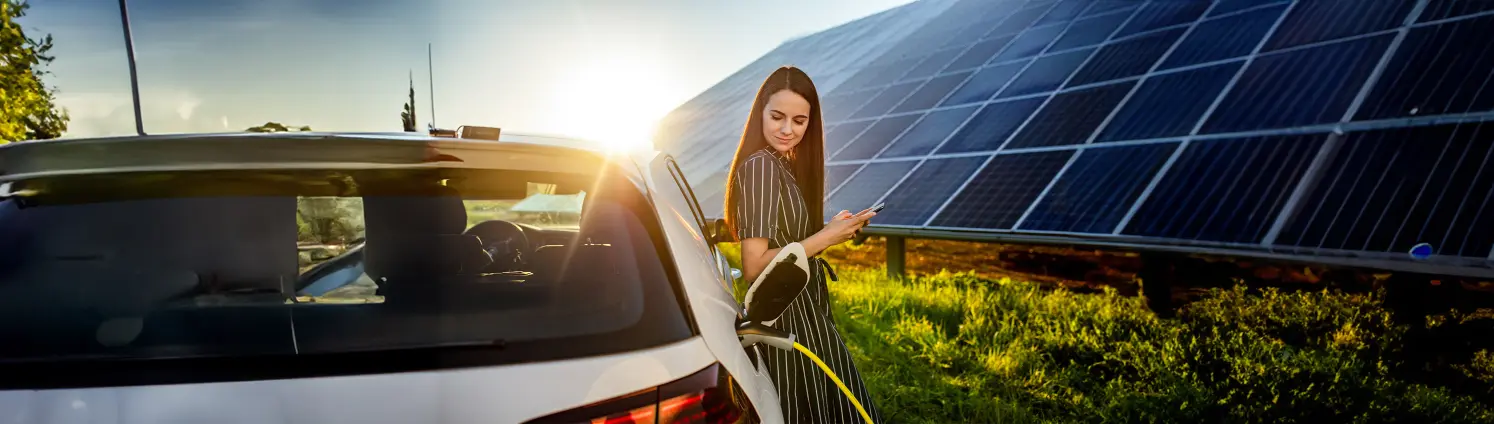 Eine Frau steht vor einem E-Auto und Solaranlage